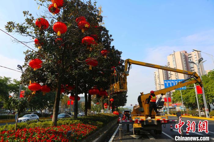 工作人员正在为街头的大树挂红灯笼。　李攀 摄