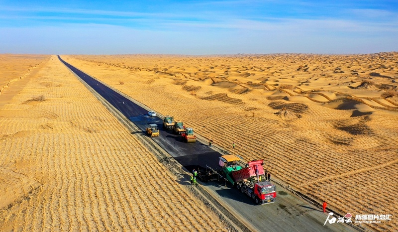 机械设备在兵团三十八团至塔中沙漠公路施工现场铺油作业（11月12日摄）。（摄影：李嘉成）